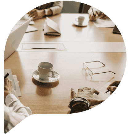 People at a meeting table with cups and saucers and notes